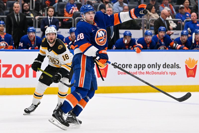 Nov 27, 2024; Elmont, New York, USA;  New York Islanders defenseman Alexander Romanov (28) stops the puck with his hand in front of Boston Bruins center Pavel Zacha (18) during the third period at UBS Arena. Mandatory Credit: Dennis Schneidler-Imagn Images