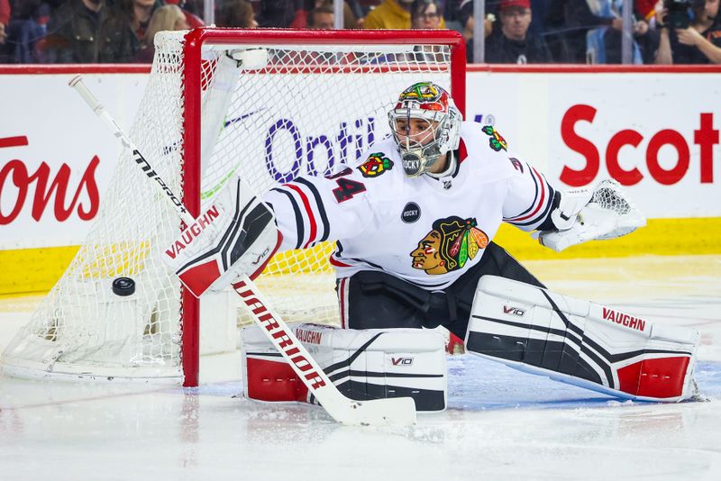 Jan 27, 2024; Calgary, Alberta, CAN; Chicago Blackhawks goaltender Petr Mrazek (34) reaches for the puck against the Calgary Flames during the second period at Scotiabank Saddledome. Mandatory Credit: Sergei Belski-USA TODAY Sports