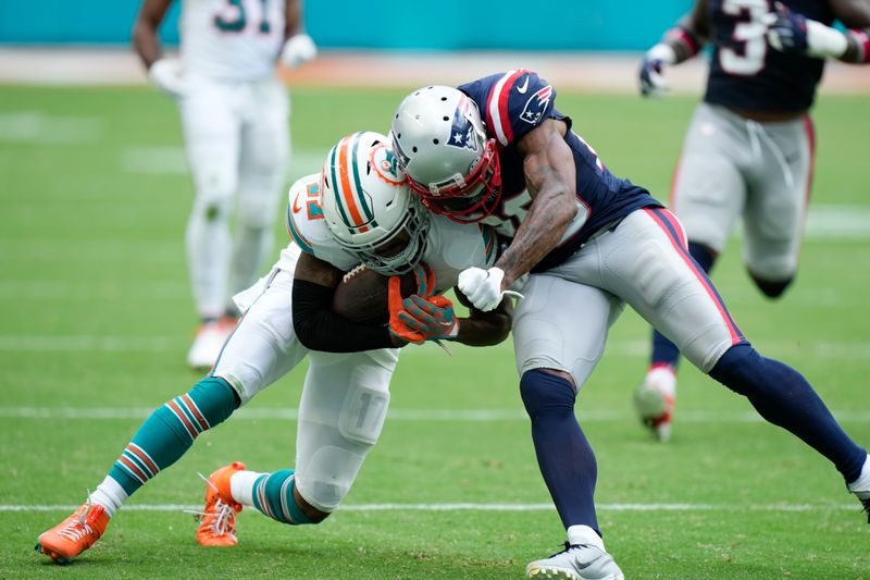 Miami Dolphins wide receiver Jaylen Waddle, left, is tackled by New England Patriots cornerback J.C. Jackson during the second half of an NFL football game, Sunday, Oct. 29, 2023, in Miami Gardens, Fla. (AP Photo/Wilfredo Lee)