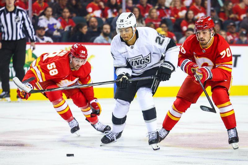 Nov 11, 2024; Calgary, Alberta, CAN; Los Angeles Kings center Akil Thomas (26) and Calgary Flames left wing Ryan Lomberg (70) battles for the puck during the first period at Scotiabank Saddledome. Mandatory Credit: Sergei Belski-Imagn Images