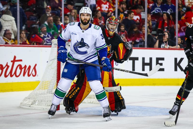 Dec 31, 2024; Calgary, Alberta, CAN; Vancouver Canucks left wing Phillip Di Giuseppe (34) screens in front of Calgary Flames goaltender Dustin Wolf (32) during the third period at Scotiabank Saddledome. Mandatory Credit: Sergei Belski-Imagn Images