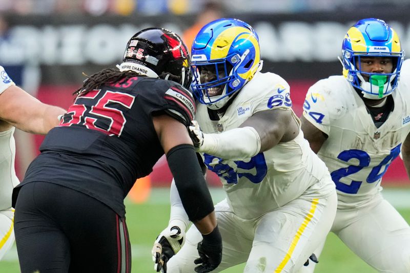 Los Angeles Rams guard Kevin Dotson, center, blocks for Rams running back Royce Freeman (24) against Arizona Cardinals defensive tackle Dante Stills (55) during the second half of an NFL football game Sunday, Nov. 26, 2023, in Glendale, Ariz. The Rams won 37-14. (AP Photo/Ross D. Franklin)