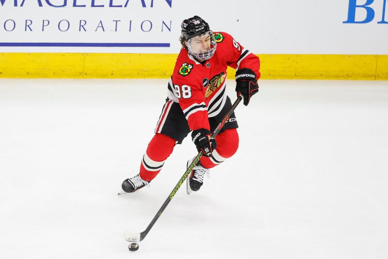 Mar 26, 2024; Chicago, Illinois, USA; Chicago Blackhawks center Connor Bedard (98) looks to pass the puck against the Calgary Flames during the second period at United Center. Mandatory Credit: Kamil Krzaczynski-USA TODAY Sports