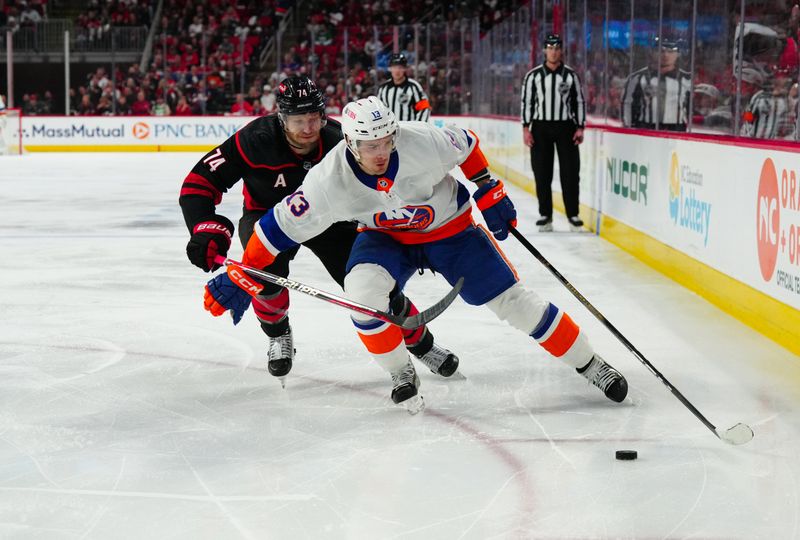 Apr 22, 2024; Raleigh, North Carolina, USA;New York Islanders center Mathew Barzal (13) skates with the puck past Carolina Hurricanes defenseman Jaccob Slavin (74) during the second period in game two of the first round of the 2024 Stanley Cup Playoffs at PNC Arena. Mandatory Credit: James Guillory-USA TODAY Sports