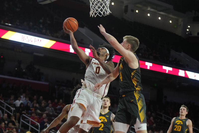 Jan 14, 2025; Los Angeles, California, USA; Southern California Trojans forward Saint Thomas (0) shoots the ball against Iowa Hawkeyes guard Josh Dix (4) in the second half at the Galen Center. Mandatory Credit: Kirby Lee-Imagn Images