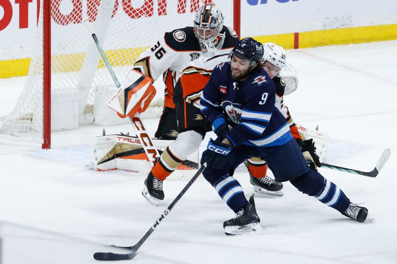 Mar 15, 2024; Winnipeg, Manitoba, CAN; Winnipeg Jets forward Alex Iafallo (9) tries to skates away from Anaheim Ducks defenseman Pavel Mintyukov (34) during the third period at Canada Life Centre. Mandatory Credit: Terrence Lee-USA TODAY Sports