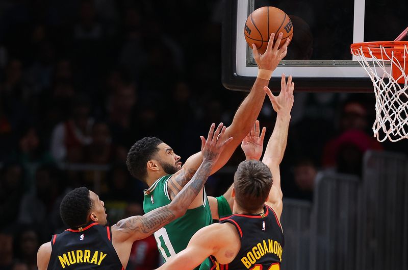 ATLANTA, GEORGIA - MARCH 28:  Jayson Tatum #0 of the Boston Celtics draws a foul as he drives against Dejounte Murray #5 and Bogdan Bogdanovic #13 of the Atlanta Hawks during overtime at State Farm Arena on March 28, 2024 in Atlanta, Georgia.  NOTE TO USER: User expressly acknowledges and agrees that, by downloading and/or using this photograph, user is consenting to the terms and conditions of the Getty Images License Agreement.  (Photo by Kevin C. Cox/Getty Images)