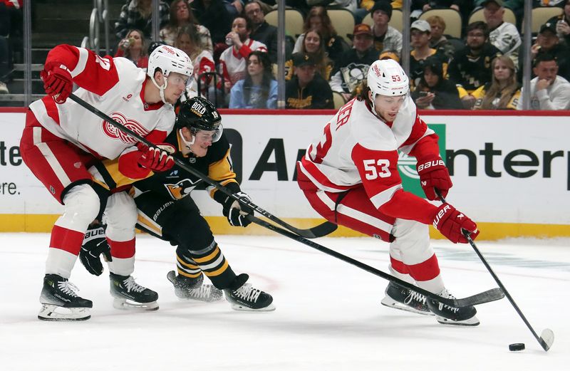 Nov 13, 2024; Pittsburgh, Pennsylvania, USA;  Detroit Red Wings defenseman Moritz Seider (53) moves the puck against pressure from Pittsburgh Penguins right wing Jesse Puljujarvi (18) as Detroit defenseman Simon Edvinsson (77) checks Puljujarvi during the third period at PPG Paints Arena. Mandatory Credit: Charles LeClaire-Imagn Images