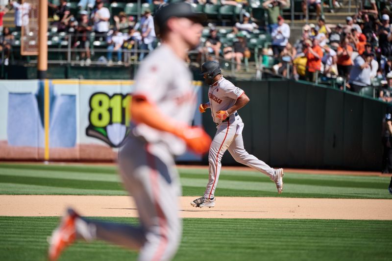 Aug 18, 2024; Oakland, California, USA; San Francisco Giants outfielder Jerar Encarnacion (59) runs the bases with infielder Matt Chapman (26) after hitting a two-run home run against the Oakland Athletics during the tenth inning at Oakland-Alameda County Coliseum. Mandatory Credit: Robert Edwards-USA TODAY Sports