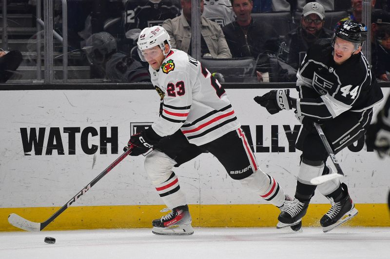 Apr 18, 2024; Los Angeles, California, USA; Chicago Blackhawks center Philipp Kurashev (23) moves the puck ahead of Los Angeles Kings defenseman Mikey Anderson (44) during the first period at Crypto.com Arena. Mandatory Credit: Gary A. Vasquez-USA TODAY Sports