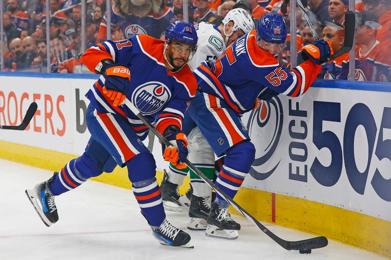 May 14, 2024; Edmonton, Alberta, CAN; Edmonton Oilers forward Evander Kane (91) clears a puck from a battle between forward Dylan Holloway (55) and Vancouver Canucks forward Teddy Blueger (53) during the first period in game four of the second round of the 2024 Stanley Cup Playoffs at Rogers Place. Mandatory Credit: Perry Nelson-USA TODAY Sports