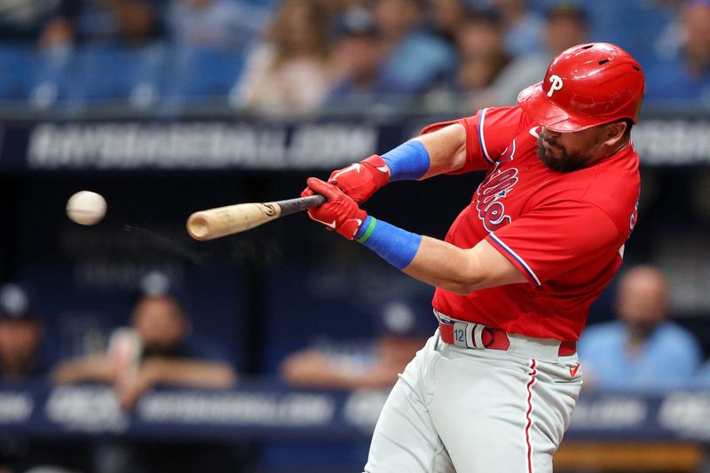 Jul 6, 2023; St. Petersburg, Florida, USA;  Philadelphia Phillies left fielder Kyle Schwarber (12) hits a double against the Tampa Bay Rays in the first inning at Tropicana Field. Mandatory Credit: Nathan Ray Seebeck-USA TODAY Sports