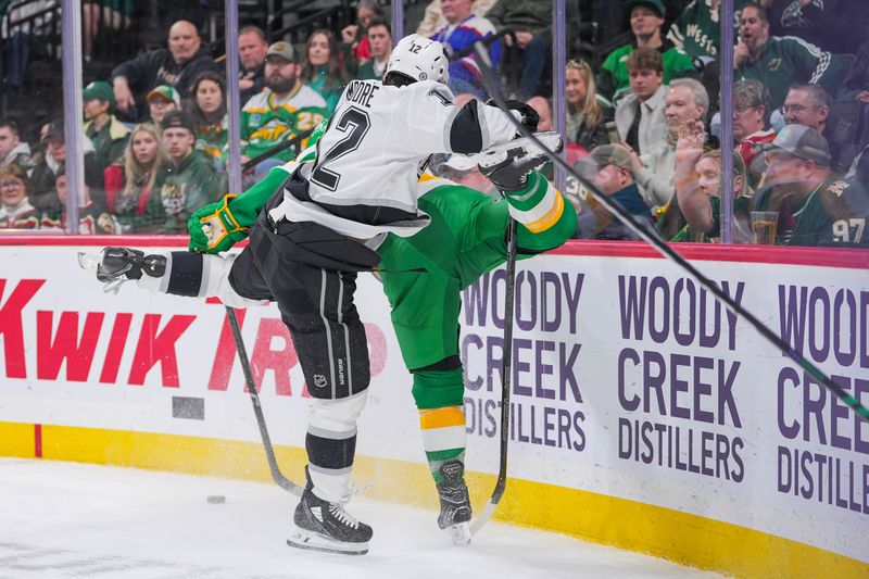 Mar 17, 2025; Saint Paul, Minnesota, USA;  Los Angeles Kings left wing Trevor Moore (12) checks Minnesota Wild right wing Ryan Hartman (38) in the first period at Xcel Energy Center. Mandatory Credit: Brad Rempel-Imagn Images