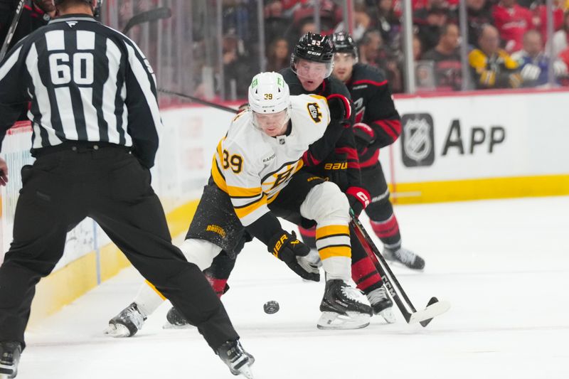 Apr 7, 2026; Raleigh, North Carolina, USA;  Carolina Hurricanes right wing Jackson Blake (53) and Boston Bruins center Morgan Geekie (39) battle over the puck during the third period at Lenovo Center. Mandatory Credit: James Guillory-Imagn Images