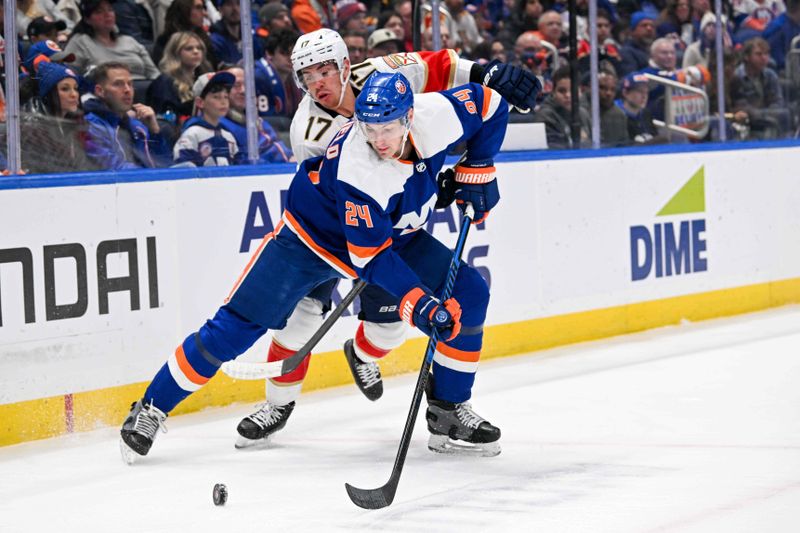 Jan 27, 2024; Elmont, New York, USA; New York Islanders defenseman Scott Mayfield (24) and Florida Panthers center Evan Rodrigues (17) battle for the puck during the first period at UBS Arena. Mandatory Credit: Dennis Schneidler-USA TODAY Sports