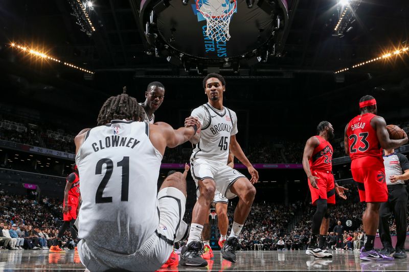 BROOKLYN, NY - OCTOBER 18: Noah Clowney #21 of the Brooklyn Nets is helped to his feet by teammates Dennis Schroder #17 and Keon Johnson #45 during the game against the Toronto Raptors on October 18, 2024 at Barclays Center in Brooklyn, New York. NOTE TO USER: User expressly acknowledges and agrees that, by downloading and or using this Photograph, user is consenting to the terms and conditions of the Getty Images License Agreement. Mandatory Copyright Notice: Copyright 2024 NBAE (Photo by Nathaniel S. Butler/NBAE via Getty Images)