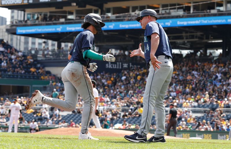 Aug 18, 2024; Pittsburgh, Pennsylvania, USA;  Seattle Mariners third base coach Manny Acta (14) greets third baseman Josh Rojas (4) circling the bases on a solo home run against the Pittsburgh Pirates during the fourth inning at PNC Park. Mandatory Credit: Charles LeClaire-USA TODAY Sports