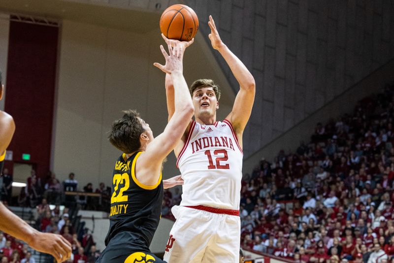 Feb 28, 2023; Bloomington, Indiana, USA; Indiana Hoosiers forward Miller Kopp (12) shoots the ball while Iowa Hawkeyes forward Patrick McCaffery (22) defends in the first half at Simon Skjodt Assembly Hall. Mandatory Credit: Trevor Ruszkowski-USA TODAY Sports