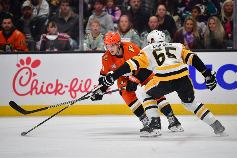 Jan 23, 2025; Anaheim, California, USA; Anaheim Ducks right wing Troy Terry (19) moves the puck against Pittsburgh Penguins defenseman Erik Karlsson (65) during the first period at Honda Center. Mandatory Credit: Gary A. Vasquez-Imagn Images