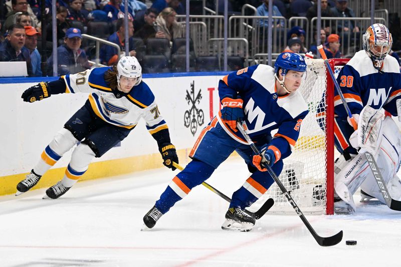 Mar 5, 2024; Elmont, New York, USA;  New York Islanders defenseman Sebastian Aho (25) skates the puck from behind the net chased by St. Louis Blues center Oskar Sundqvist (70) during the first period at UBS Arena. Mandatory Credit: Dennis Schneidler-USA TODAY Sports