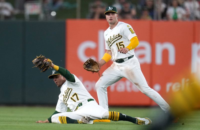 May 21, 2025; West Sacramento, California, USA; Athletics second baseman Luis Urias (17) holds onto the ball after making a catch in front of center fielder Seth Brown (15) against the Los Angeles Angels in the fourth inning at Sutter Health Park. Mandatory Credit: Cary Edmondson-Imagn Images