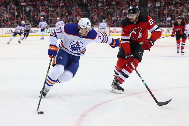 Dec 21, 2023; Newark, New Jersey, USA; Edmonton Oilers left wing Warren Foegele (37) skates with the puck while being defended by New Jersey Devils defenseman Kevin Bahl (88) during the first period at Prudential Center. Mandatory Credit: Ed Mulholland-USA TODAY Sports