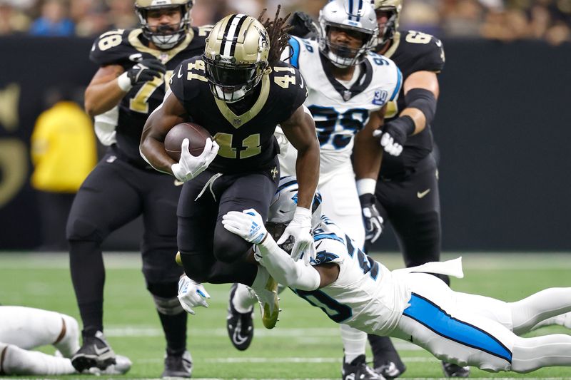 New Orleans Saints running back Alvin Kamara (41) is tripped up by Carolina Panthers safety Jordan Fuller (20) during an NFL football game, Sunday, Sept. 8, 2024, in New Orleans. (AP Photo/Tyler Kaufman)