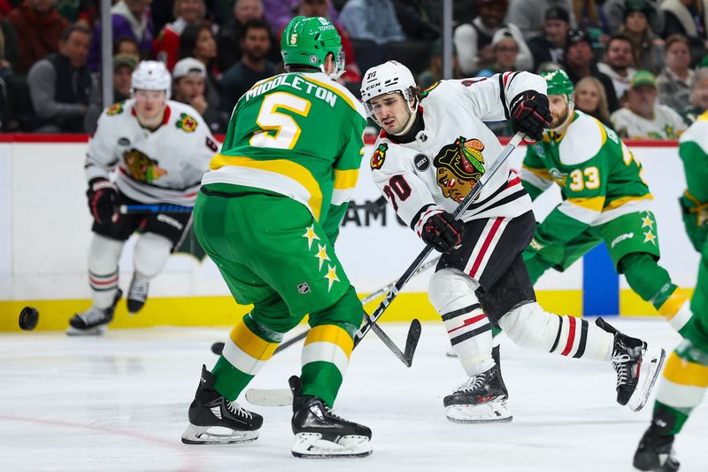 Dec 3, 2023; Saint Paul, Minnesota, USA; Chicago Blackhawks center Cole Guttman (70) shoots against Minnesota Wild defenseman Jake Middleton (5) during the third period at Xcel Energy Center. Mandatory Credit: Matt Krohn-USA TODAY Sports