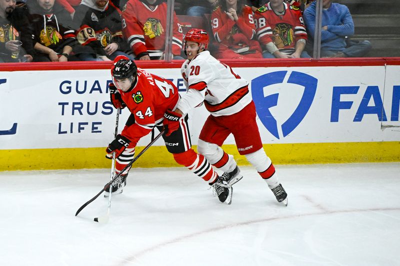 Jan 20, 2025; Chicago, Illinois, USA;  Chicago Blackhawks defenseman Wyatt Kaiser (44) and Carolina Hurricanes center Sebastian Aho (20) chase the puck during the third period at the United Center. Mandatory Credit: Matt Marton-Imagn Images