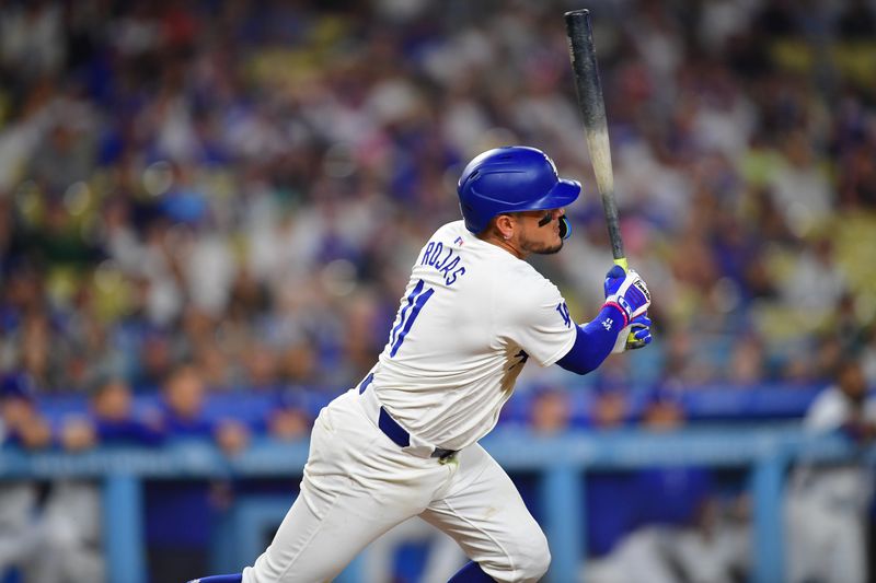 Aug 27, 2024; Los Angeles, California, USA; Los Angeles Dodgers shortstop Miguel Rojas (11) hits a single against the Baltimore Orioles during the ninth inning at Dodger Stadium. Mandatory Credit: Gary A. Vasquez-USA TODAY Sports