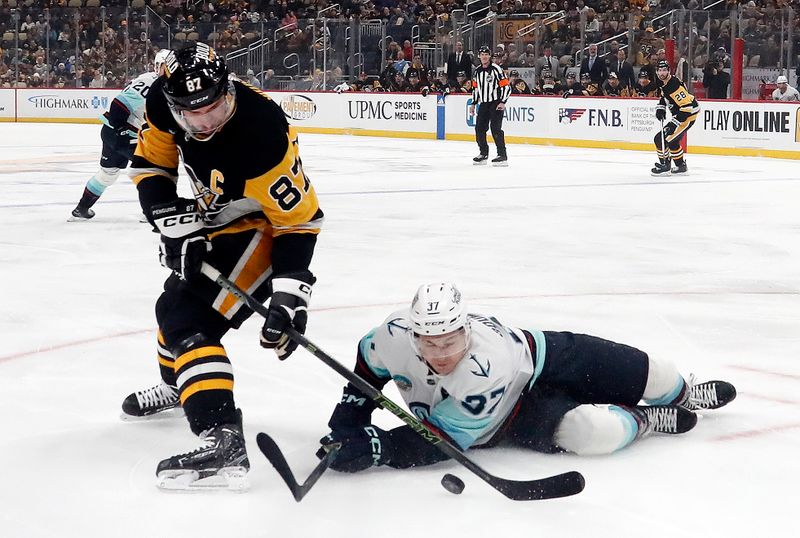 Jan 15, 2024; Pittsburgh, Pennsylvania, USA; Pittsburgh Penguins center Sidney Crosby (87) plays the puck as  Seattle Kraken center Yanni Gourde (37) falls to the ice during the first period at PPG Paints Arena. Mandatory Credit: Charles LeClaire-USA TODAY Sports