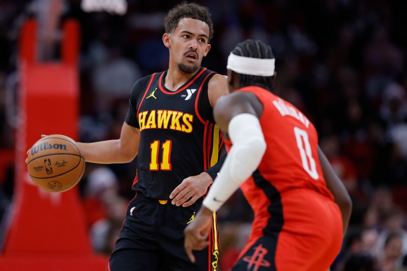 HOUSTON, TEXAS - DECEMBER 20: Trae Young #11 of the Atlanta Hawks controls the ball ahead of Aaron Holiday #0 of the Houston Rockets during the first half at Toyota Center on December 20, 2023 in Houston, Texas. User expressly acknowledges and agrees that, by downloading and or using this photograph, User is consenting to the terms and conditions of the Getty Images License Agreement.?  (Photo by Carmen Mandato/Getty Images)