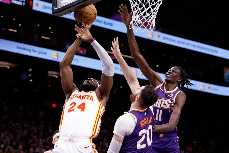 PHOENIX, ARIZONA - MARCH 21: Bruno Fernando #24 of the Atlanta Hawks puts up a shot against Jusuf Nurkic #20 and Bol Bol #11 of the Phoenix Suns during the first half at Footprint Center on March 21, 2024 in Phoenix, Arizona. NOTE TO USER: User expressly acknowledges and agrees that, by downloading and or using this photograph, User is consenting to the terms and conditions of the Getty Images License Agreement.  (Photo by Chris Coduto/Getty Images)