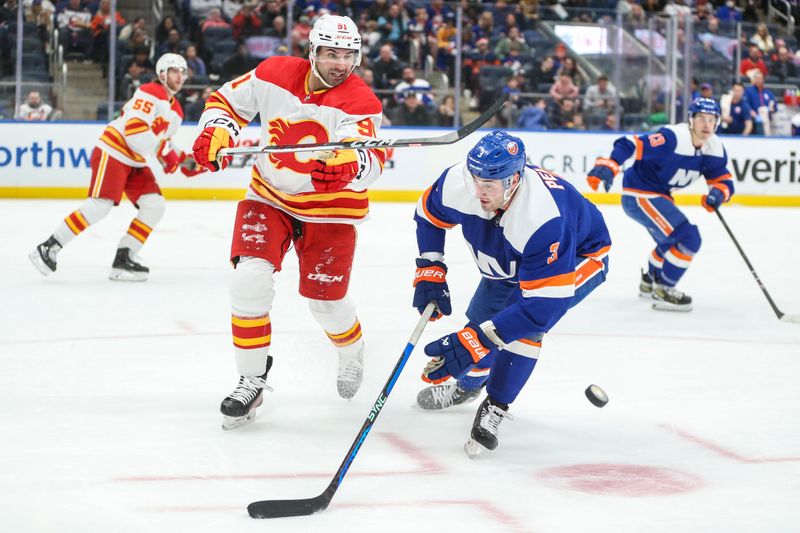 Feb 10, 2024; Elmont, New York, USA;  Calgary Flames center Nazem Kadri (91) and New York Islanders defenseman Adam Pelech (3) battle for control of the puck in the second period at UBS Arena. Mandatory Credit: Wendell Cruz-USA TODAY Sports