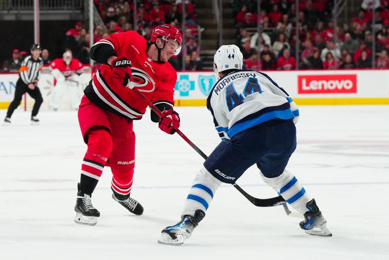 Mar 2, 2024; Raleigh, North Carolina, USA; Carolina Hurricanes right wing Andrei Svechnikov (37) takes a shot past Winnipeg Jets defenseman Josh Morrissey (44) during the first period at PNC Arena. Mandatory Credit: James Guillory-USA TODAY Sports