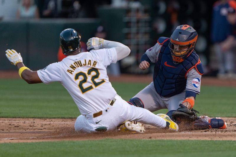 Jul 23, 2024; Oakland, California, USA;  Oakland Athletics outfielder Miguel Andujar (22) slides at home plate against Houston Astros catcher Victor Caratini (17) during the fifth inning at Oakland-Alameda County Coliseum. Mandatory Credit: Stan Szeto-USA TODAY Sports