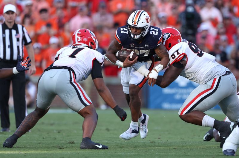 Sep 30, 2023; Auburn, Alabama, USA; Auburn Tigers running back Jarquez Hunter (27) is tackled by Georgia Bulldogs linebacker Marvin Jones Jr. (7) and defensive lineman Warren Brinson (97) during the fourth quarter at Jordan-Hare Stadium. Mandatory Credit: John Reed-USA TODAY Sports