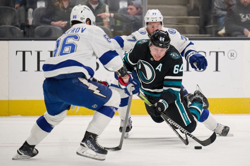 Mar 21, 2024; San Jose, California, USA; San Jose Sharks center Mikael Granlund (64) plays the puck against Tampa Bay Lightning defenseman Victor Hedman (77) and right wing Nikita Kucherov (86) during the second period at SAP Center at San Jose. Mandatory Credit: Robert Edwards-USA TODAY Sports