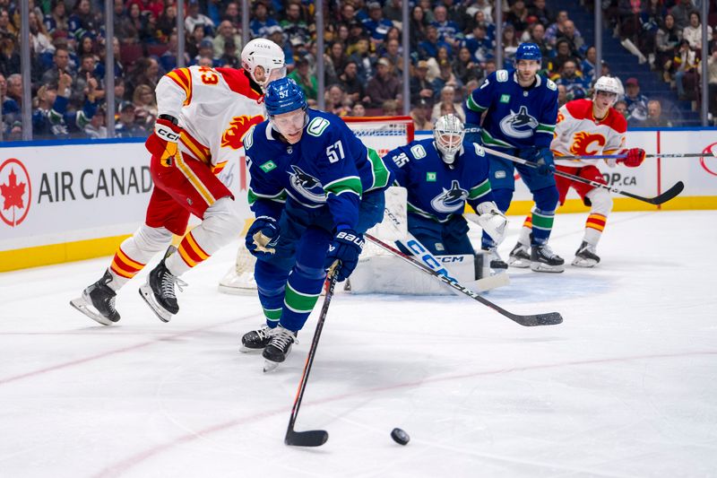 Apr 16, 2024; Vancouver, British Columbia, CAN; Vancouver Canucks defenseman Tyler Myers (57) reaches for the loose puck against the Calgary Flames in the second period at Rogers Arena. Mandatory Credit: Bob Frid-USA TODAY Sports