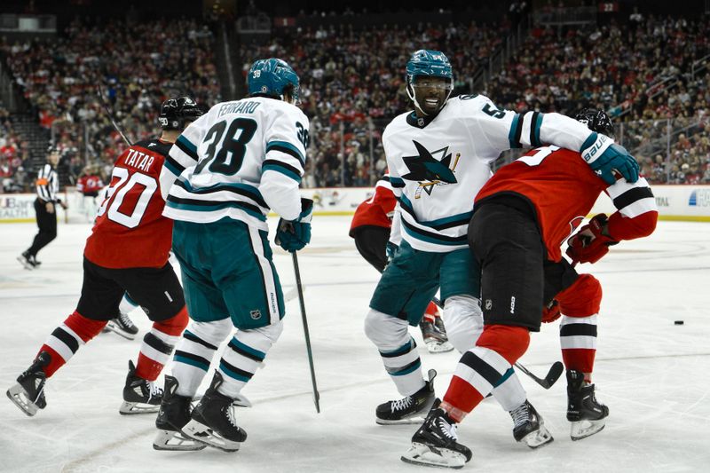 Nov 10, 2024; Newark, New Jersey, USA; San Jose Sharks right wing Givani Smith (54) and New Jersey Devils left wing Kurtis MacDermid (23) compete for the puck during the second period at Prudential Center. Mandatory Credit: John Jones-Imagn Images