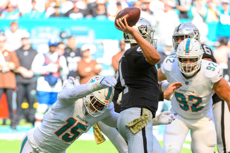 Las Vegas Raiders quarterback Aidan O'Connell (4) throws the ball under pressure from Miami Dolphins linebacker Jaelan Phillips (15) and Miami Dolphins defensive tackle Zach Sieler (92) during an NFL football game, Sunday, Nov. 19, 2023, in Miami Gardens, Fla. (AP Photo/Doug Murray)