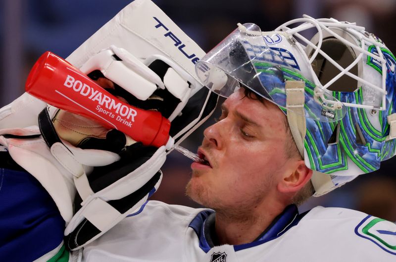 Nov 29, 2024; Buffalo, New York, USA;  Vancouver Canucks goaltender Kevin Lankinen (32) gets a drink of water during a stoppage in play against the Buffalo Sabres during the second period at KeyBank Center. Mandatory Credit: Timothy T. Ludwig-Imagn Images