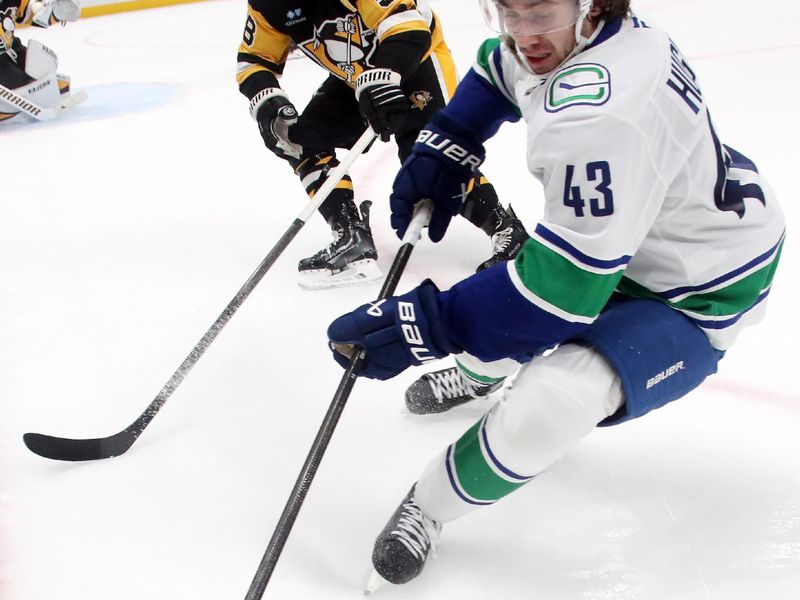 Nov 27, 2024; Pittsburgh, Pennsylvania, USA;  Vancouver Canucks defenseman Quinn Hughes (43) gathers the puck against Pittsburgh Penguins defenseman Kris Letang (58) during the second period at PPG Paints Arena. Mandatory Credit: Charles LeClaire-Imagn Images