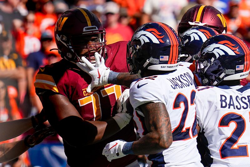 Denver Broncos safety Kareem Jackson (22) and Washington Commanders offensive tackle Saahdiq Charles (77) tangle after a hit in the end zone during an NFL football game Sunday, Sept. 10, 2023, in Denver. Jackson was disqualified ejected form the game. (AP Photo/Jack Dempsey)