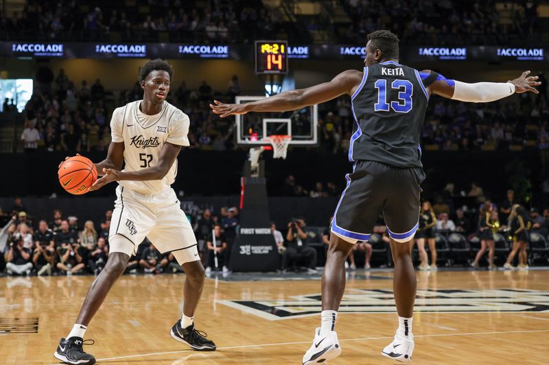 Feb 1, 2025; Orlando, Florida, USA; UCF Knights center Moustapha Thiam (52) moves the ball in front of Brigham Young Cougars center Keba Keita (13) during the first half at Addition Financial Arena. Mandatory Credit: Mike Watters-Imagn Images