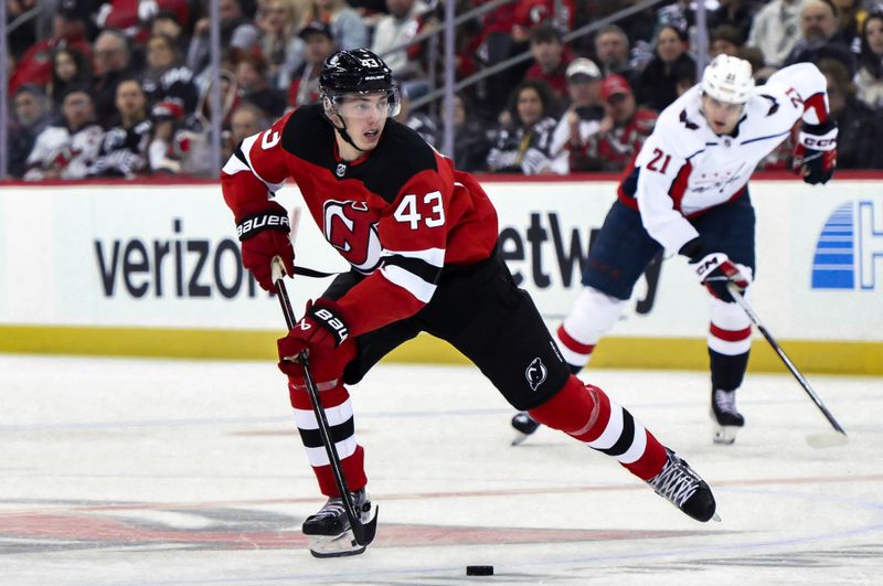 Nov 10, 2023; Newark, New Jersey, USA; New Jersey Devils defenseman Luke Hughes (43) skates with the puck against as Washington Capitals center Aliaksei Protas (21) trails the play during the second period at Prudential Center. Mandatory Credit: John Jones-USA TODAY Sports