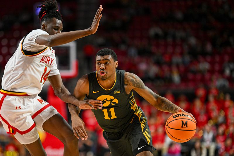 Feb 14, 2024; College Park, Maryland, USA;  Iowa Hawkeyes guard Tony Perkins (11) drive to the basket on Maryland Terrapins forward Mady Traore (14) during the fist half at Xfinity Center. Mandatory Credit: Tommy Gilligan-USA TODAY Sports