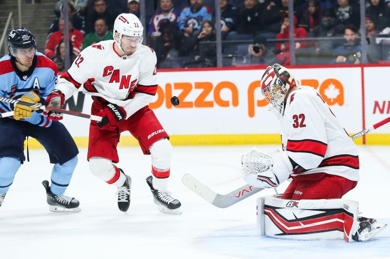 Dec 4, 2023; Winnipeg, Manitoba, CAN;   Winnipeg Jets forward Mark Scheifele (55) and Carolina Hurricanes defenseman Brett Pesce (22) look for a rebound from Carolina Hurricanes goalie Antti Raanta (32) during the second period at Canada Life Centre. Mandatory Credit: Terrence Lee-USA TODAY Sports