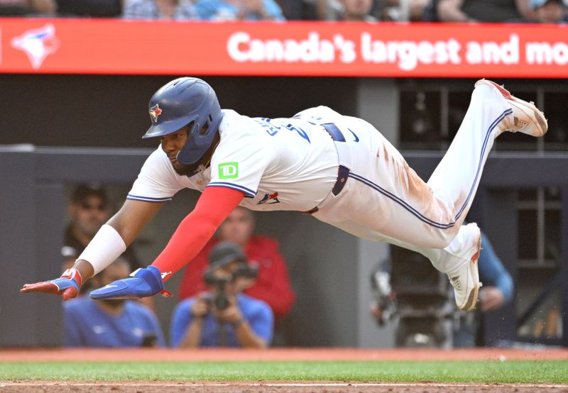 Sep 14, 2024; Toronto, Ontario, CAN;  Toronto Blue Jays first baseman Vladimir Guerrero Jr. (27) dives into home plate to score a run against the St. Louis Cardinals in the seventh inning at Rogers Centre.  Mandatory Credit: Dan Hamilton-Imagn Images