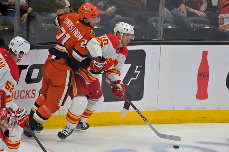 Apr 9, 2025; Anaheim, California, USA;  Anaheim Ducks center Isac Lundestrom (21) and Calgary Flames left wing Jonathan Huberdeau (10) battle along the boards during the second period at Honda Center. Mandatory Credit: Jayne Kamin-Oncea-Imagn Images